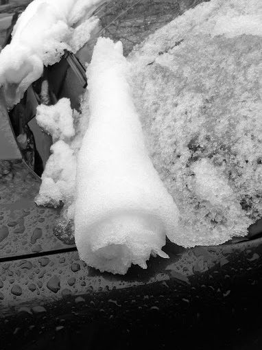 Sur un pare brise, la neige en glissant a formé un rouleau.