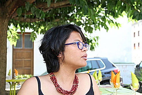 Portrait de Nathalie Muchamad à la terrasse d'un restaurant, sous un arbre.