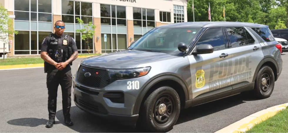 Uniformed police officer standing near patrol truck.