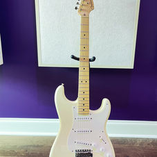 2003 Eric Clapton signature Fender Stratocaster in white, displayed on a stand against a purple wall