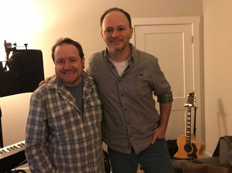 Writing session with songwriter Tony Wood and a musician, featuring a notebook and coffee cups on a table in a cozy studio