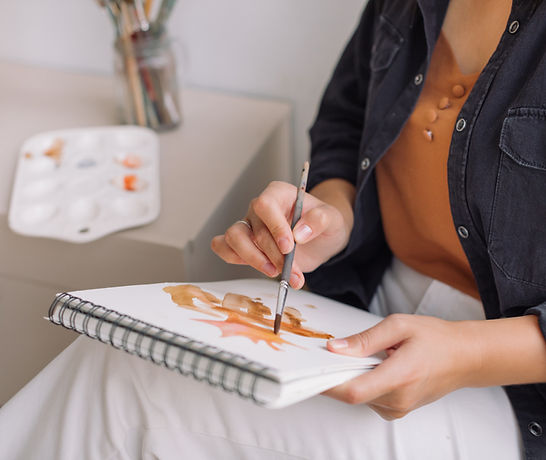 Photo of someone painting on a pad of paper in their lap