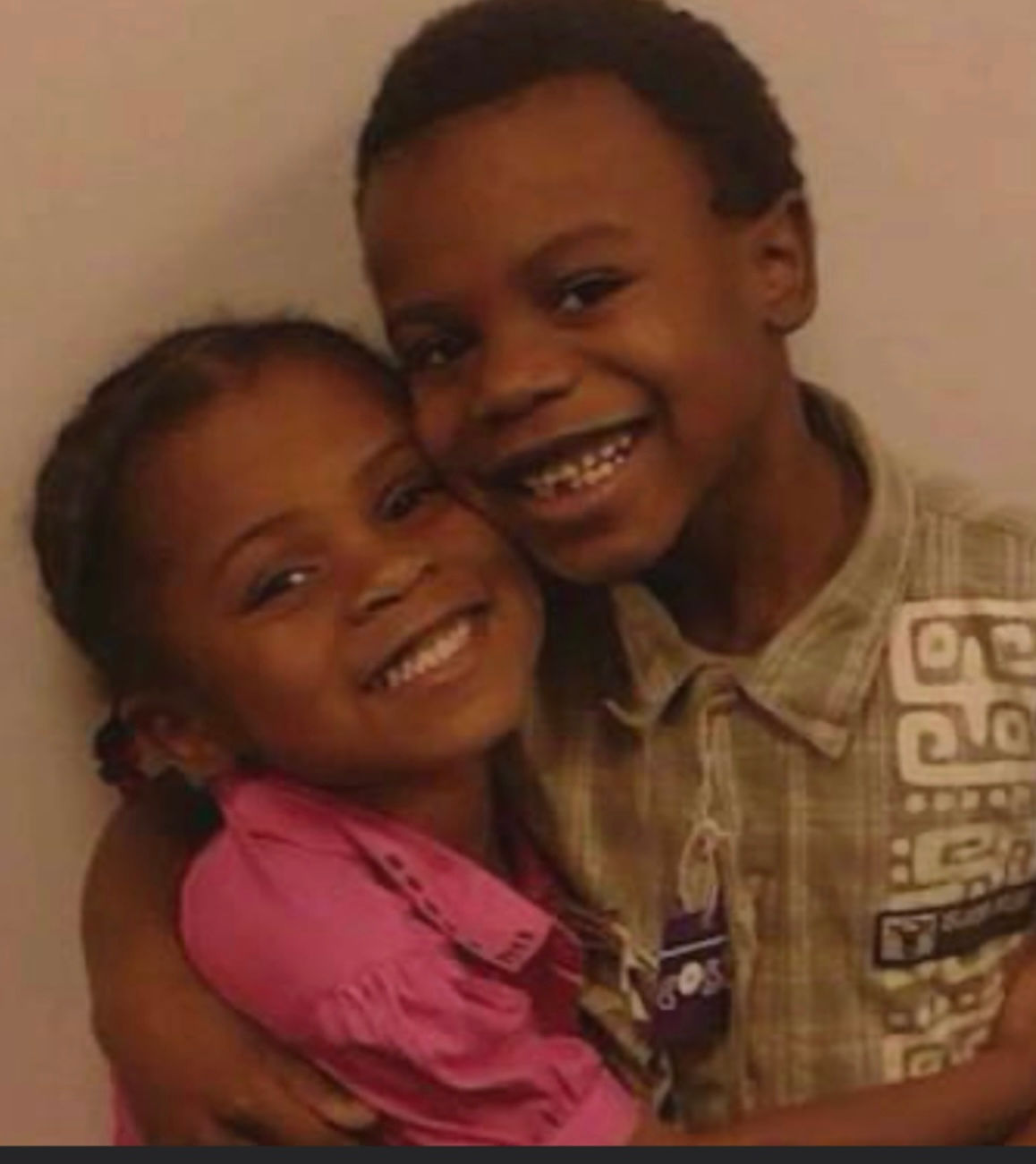 Two smiling children posing closely together for a heartwarming picture