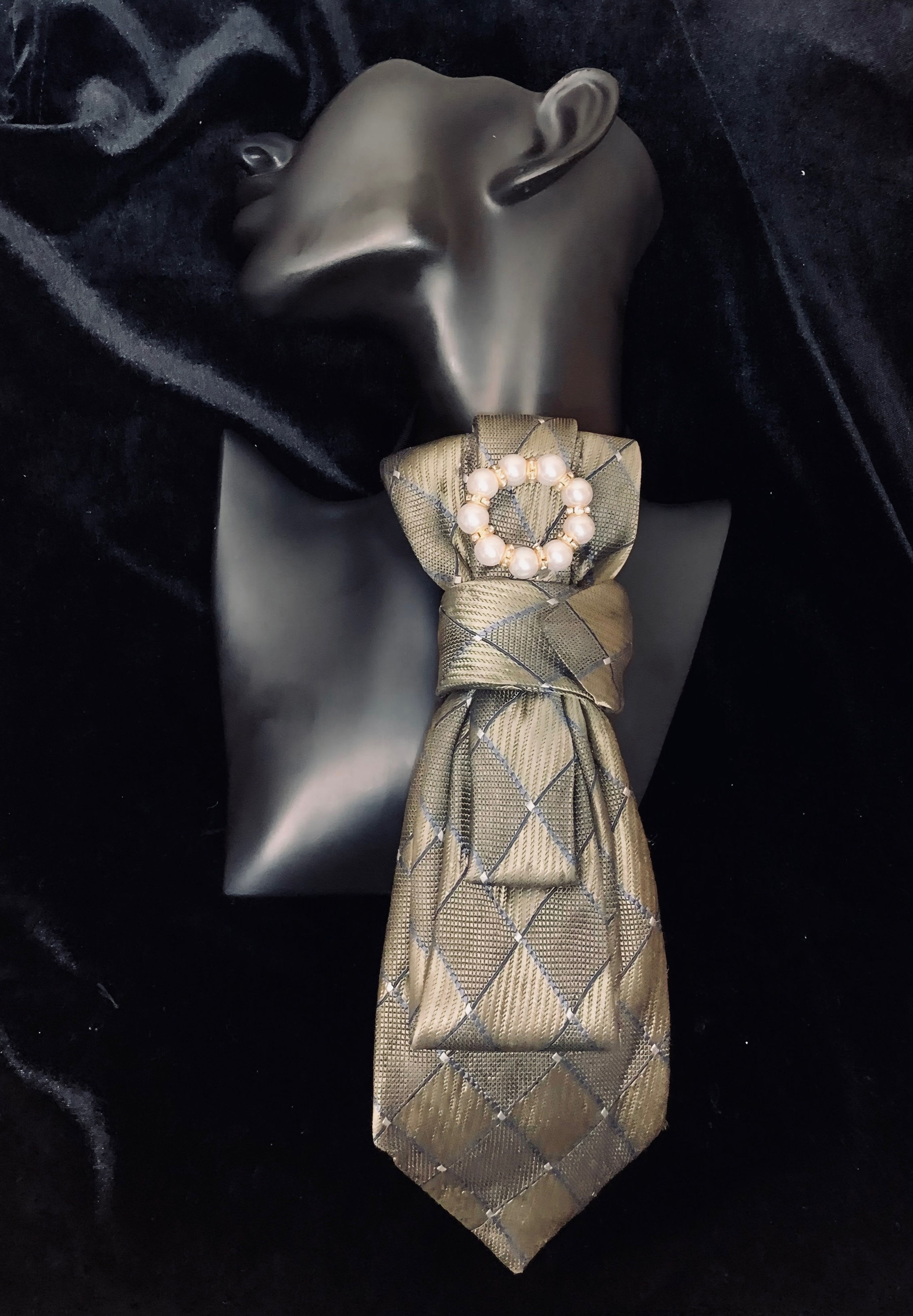 Elegant necktie with diamond pattern and brooch on a black background.