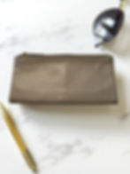 Leather wallet, pen, and sunglasses on a marble surface background.
