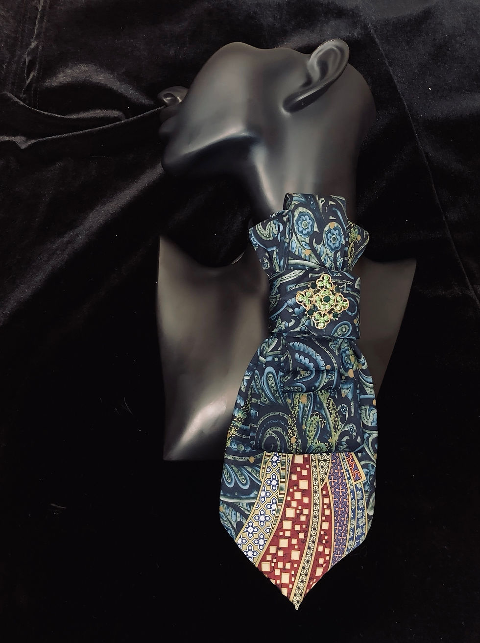 Necktie on mannequin, patterned and colorful, against a black background.