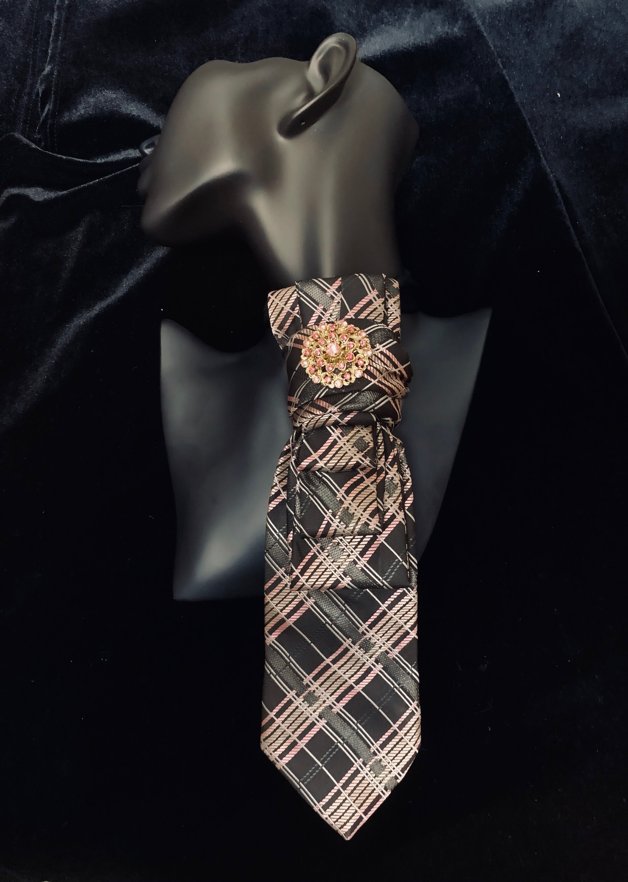 Plaid tie on a black mannequin, with floral details, against a dark fabric background.