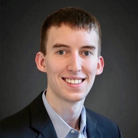 Smiling young man in a suit jacket and collared shirt.