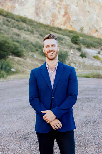 Caleb Barnard wearing a blue blazer and smiling outdoors.