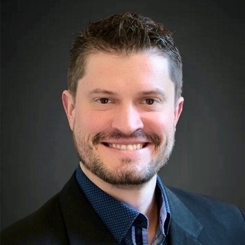 Smiling male associate with a beard in a suit.