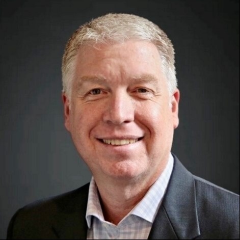 Smiling male associate with short gray hair in a suit.