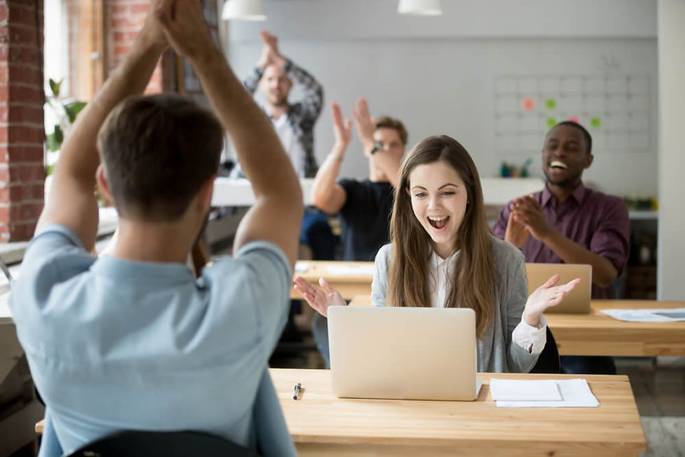 Pessoas em ambiente de trabalho comemorando uma conquista em grupo.