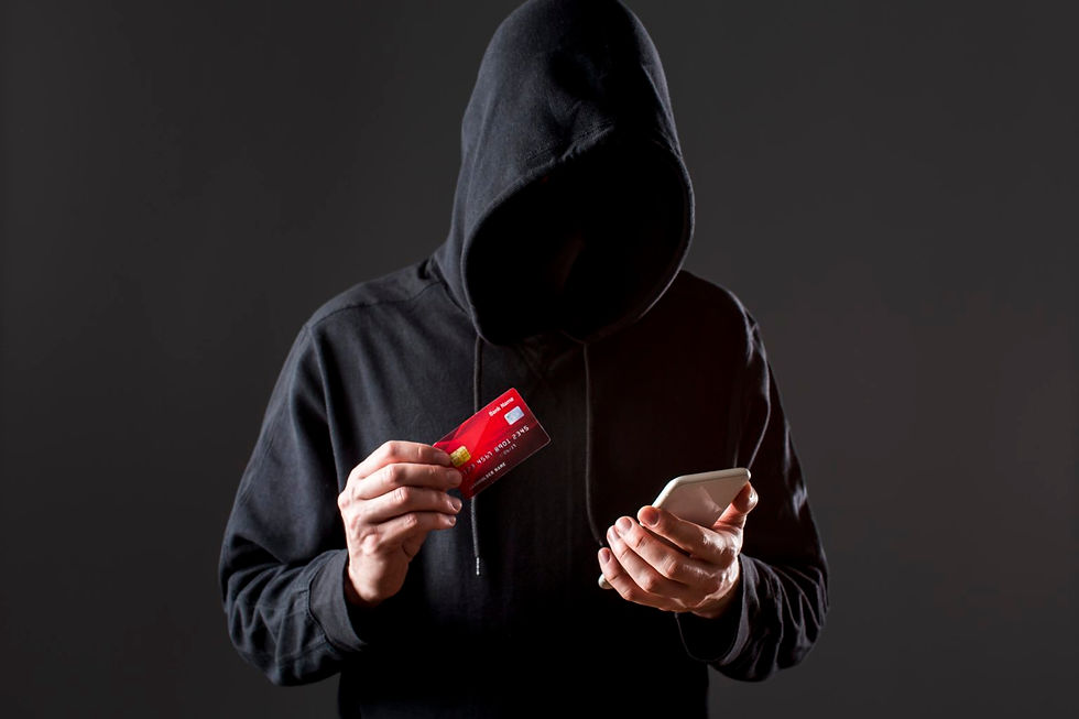 Uma pessoa vestindo um moletom preto com capuz, cobrindo o rosto, criando uma aparência misteriosa e anônima. Ela está segurando um cartão de crédito vermelho em uma mão e um celular na outra.
