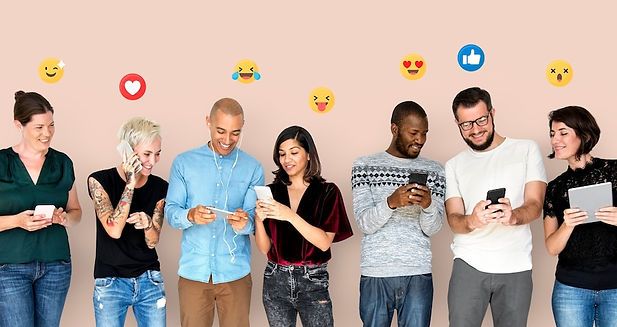 Grupo de sete pessoas sorrindo enquanto usam celulares e tablets, com ícones de reações de redes sociais (como curtidas e emojis) acima de suas cabeças, representando interação digital e engajamento nas redes sociais