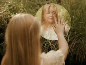 Person looking at their reflection in a calm natural setting, symbolizing parts work and EMDR therapy in Vancouver for trauma healing.