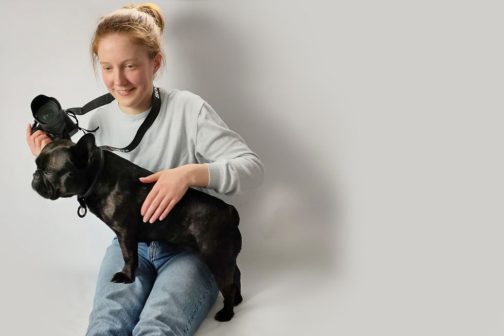 Rosie the pet photographer with a dog on her lap, holding a camera, on a studio white background