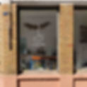 Vitrine de l'atelier de poterie et de céramique A Mains Nues, à Paris. Les murs sont en brique jaunes et roses. Une couronne de fleurs est accrochée au plafond.