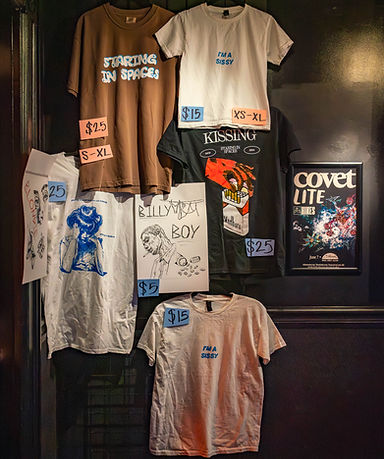 merch booth setup for staring in spaces, brown shirt, white shirts, postcard, sissy, i'm a sissy, posters of ben plays ball