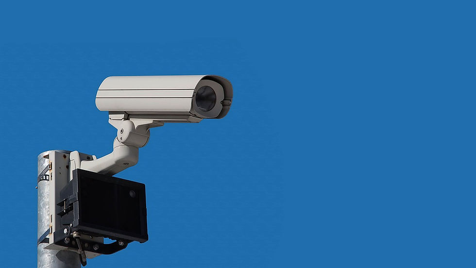 A white outdoor bullet-style CCTV camera is mounted on a pole against a clear, vibrant blue sky.