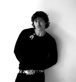 Schwarz-Weiß-Porträt eines Mannes, der an einer weißen Wand lehnt.