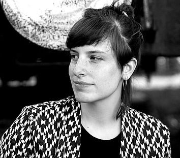 Woman with dark hair and a patterned jacket is looking away at something.