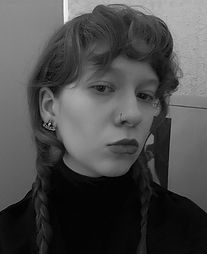 Young woman with pigtails, wearing a black turtleneck and earrings, looking at the camera