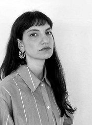 Woman with dark hair posing in front of a white background (monochrome)