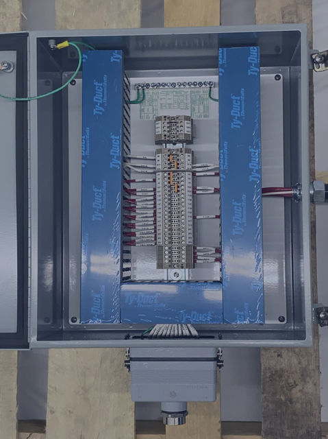 The inside of a small terminal box showing wire duct and organized wire and proper terminations of wires going to a terminal strip mounted vertically along the sub panel.