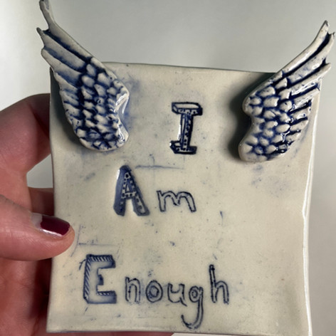 white ceramic tile with wings and text I Am Enough. blue colour highlights