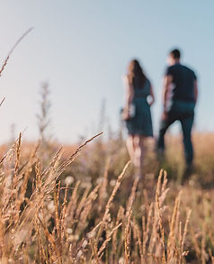 a man and a woman walking across a meadow