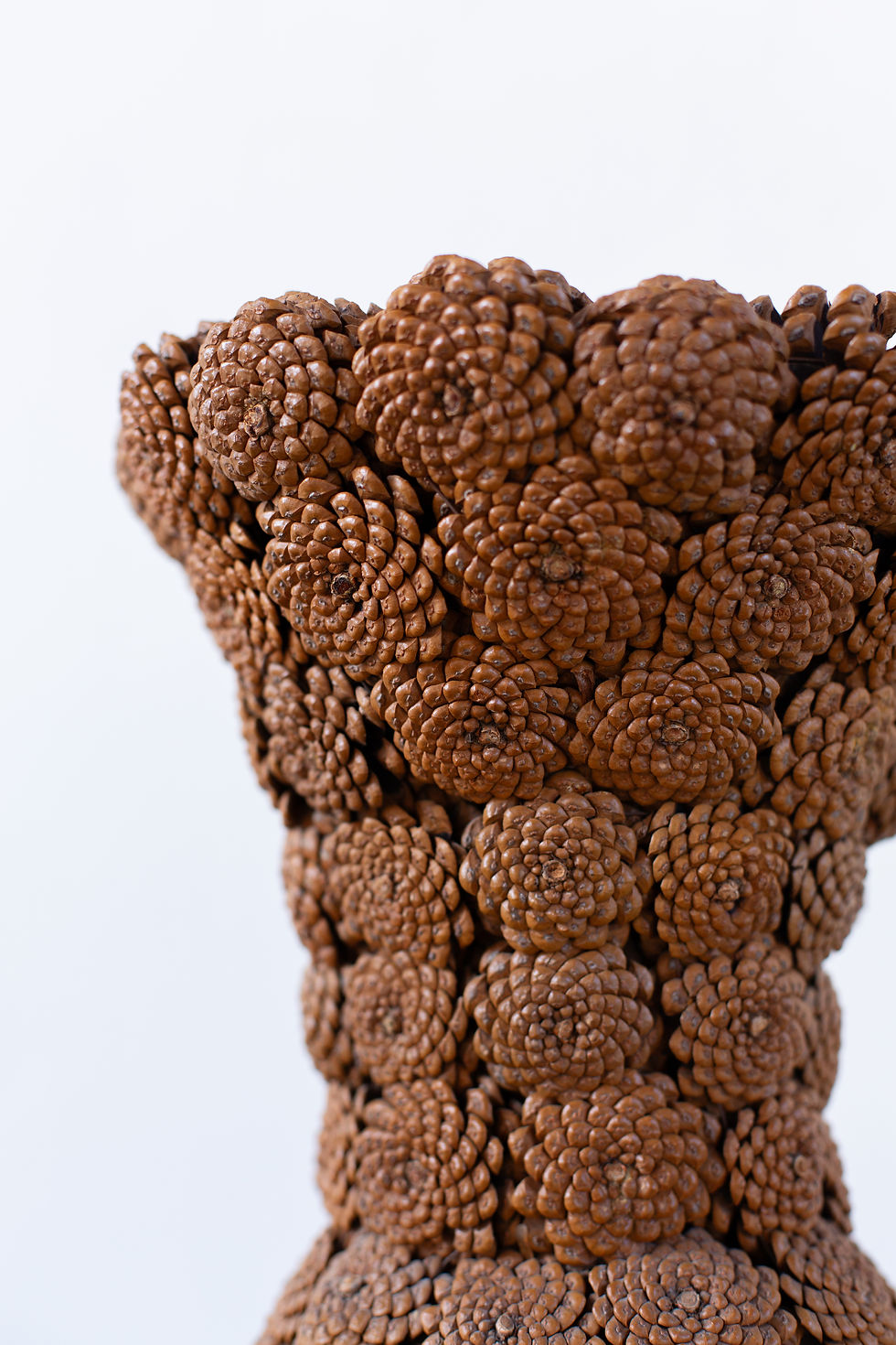 Thumbnail: A collection of folk art vessels made from hand-stitched pine cones, formed into a vase, bowl and basket.