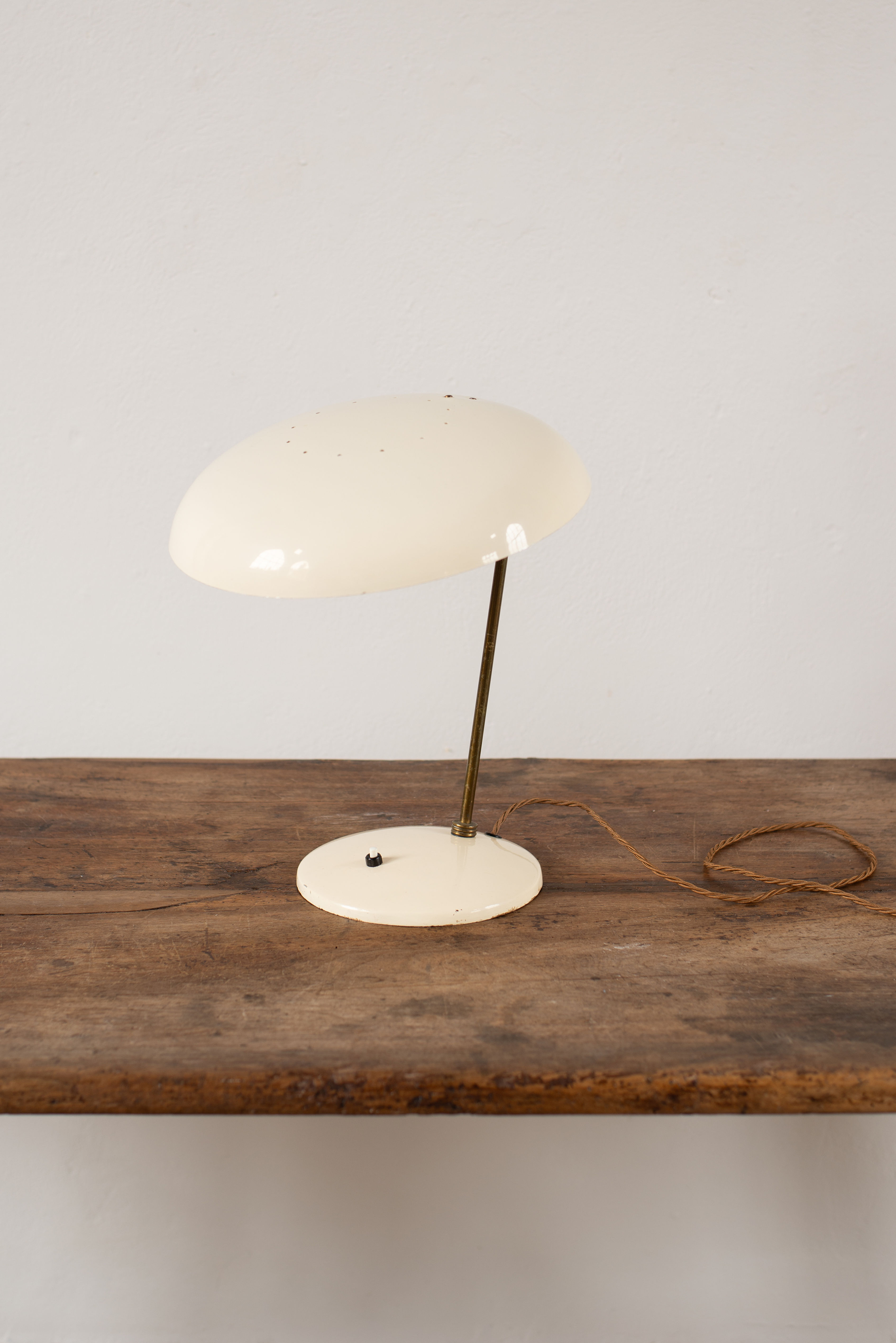 A mid-century steel desk lamp with a brass pole and cream painted finish