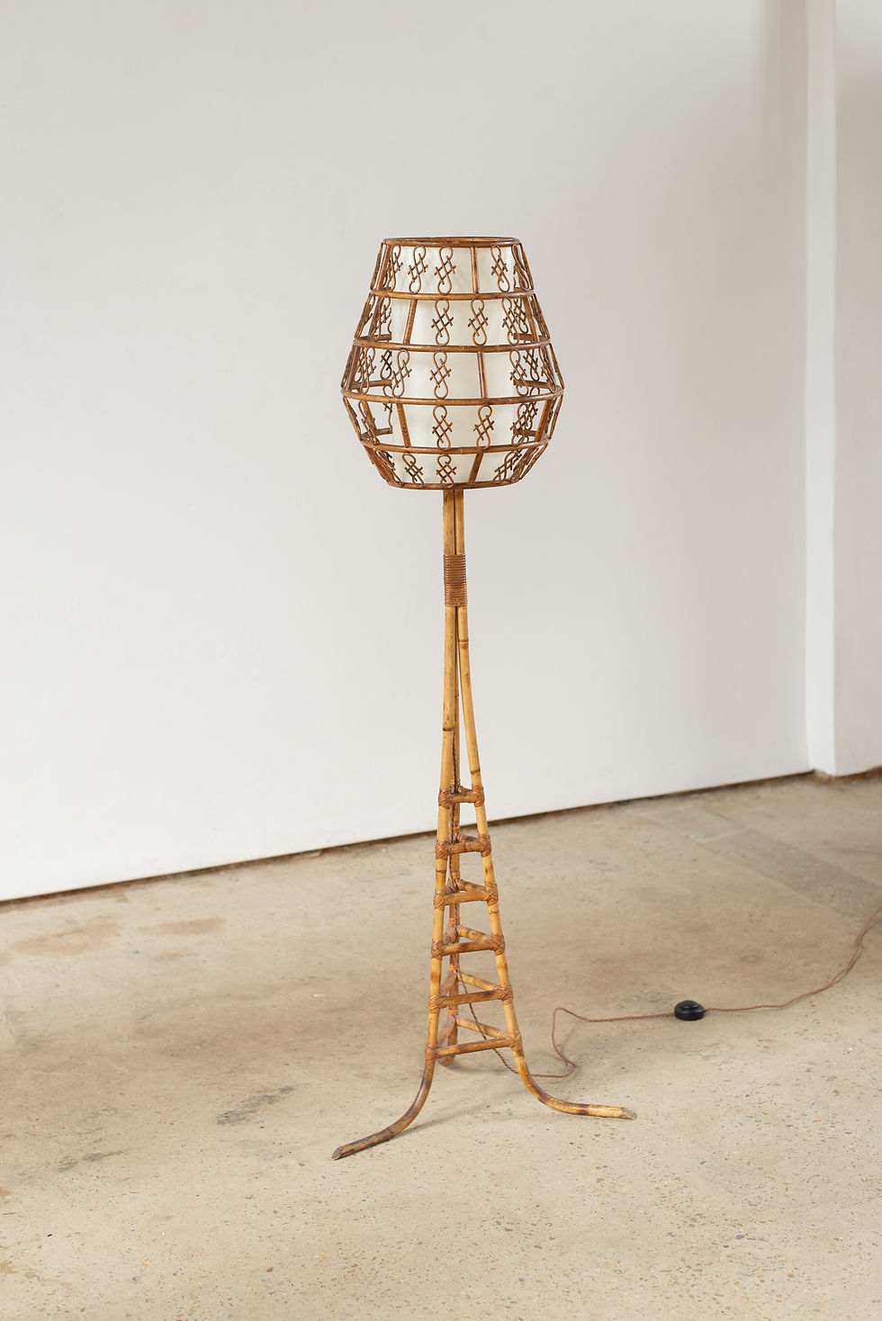 A cane floor lamp, from Italy C196O, with a tripod base and delicate decorative cane shade.