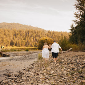 newly wed couple walking down a river bed after their wedding towards golden british columbia mountains