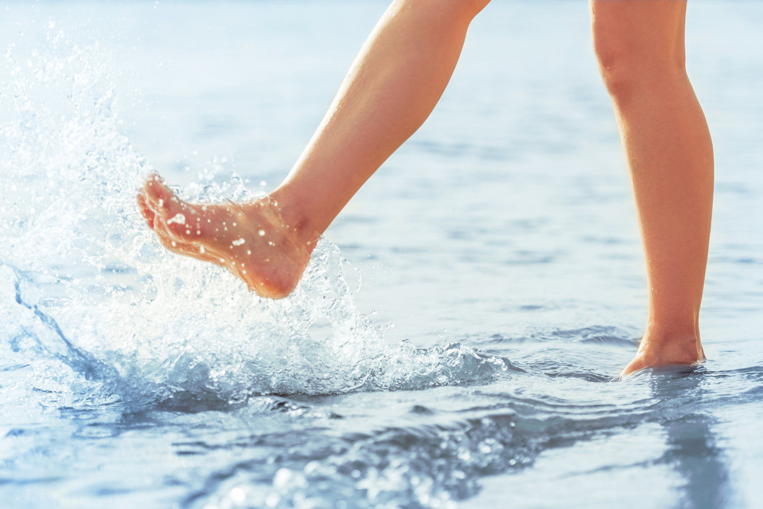 A person splashing in the sea with bare legs and feet