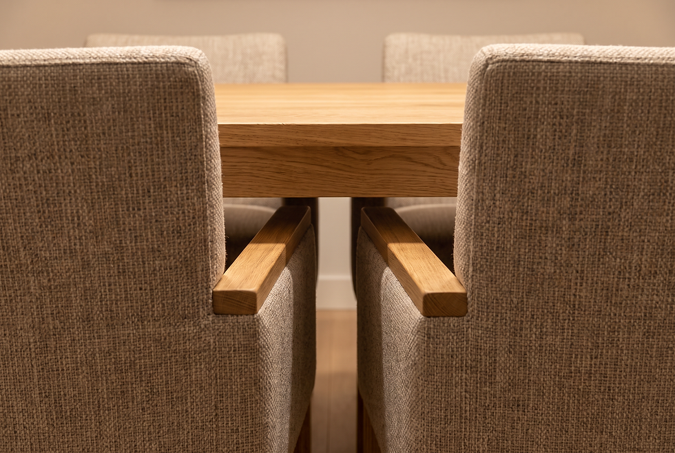 Close-up of lateral spacing and armrest clearance between two wide upholstered dining chairs at a wooden table