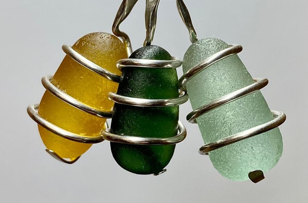 Three lozenges of sea glass in honey, green and seafoam green, are wrapped in sterling silver to create these beautiful pendants. The pendants hang from a sterling silver snake chain.
