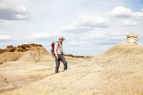 A man walking up a hill in a desert landscape