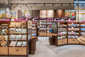 Intérieur de magasin de produits naturels avec étagères remplies de divers articles, y compris des extraits de plantes, des produits de beauté et des compléments alimentaires.