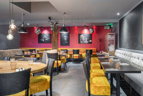 Intérieur de café moderne avec chaises jaunes, banquettes et décoration élégante.