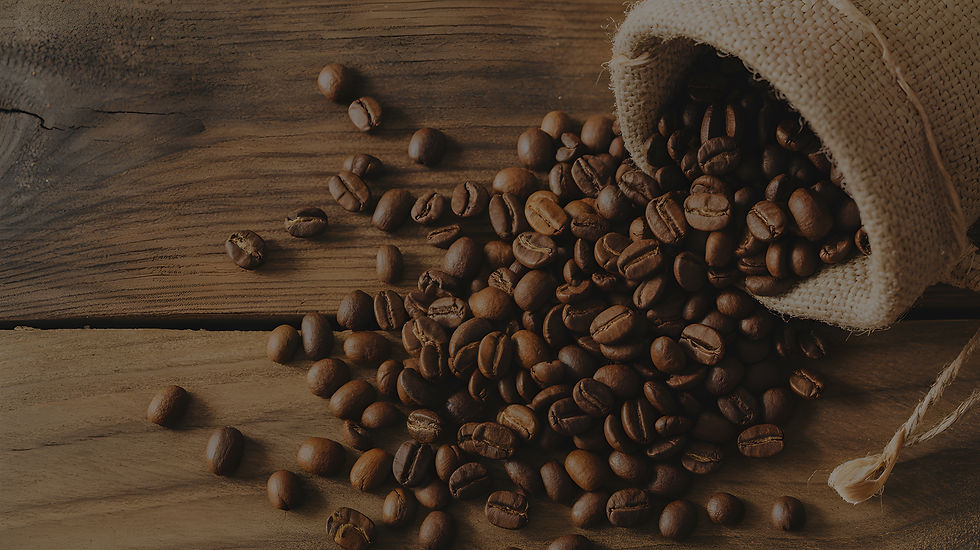 Roasted coffee beans spilled over from a sack onto a wooden table