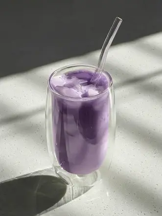 Creamy iced Ubelogy Ube latte with smooth vanilla notes in a minimalist café setting