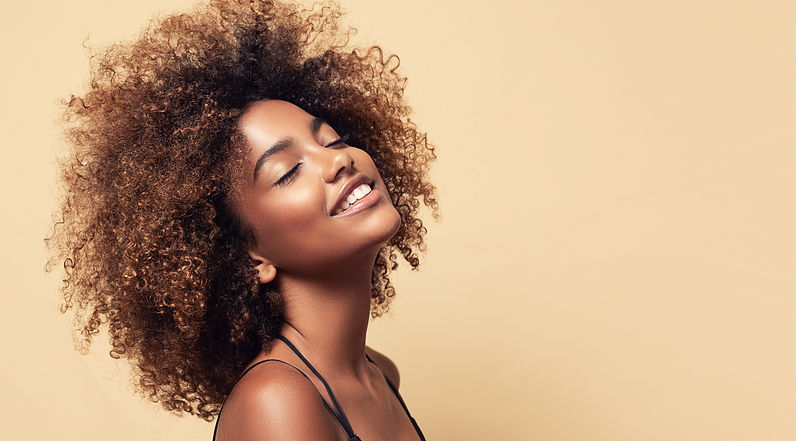 Beauty portrait of african american girl with clean healthy skin on beige background. Smil