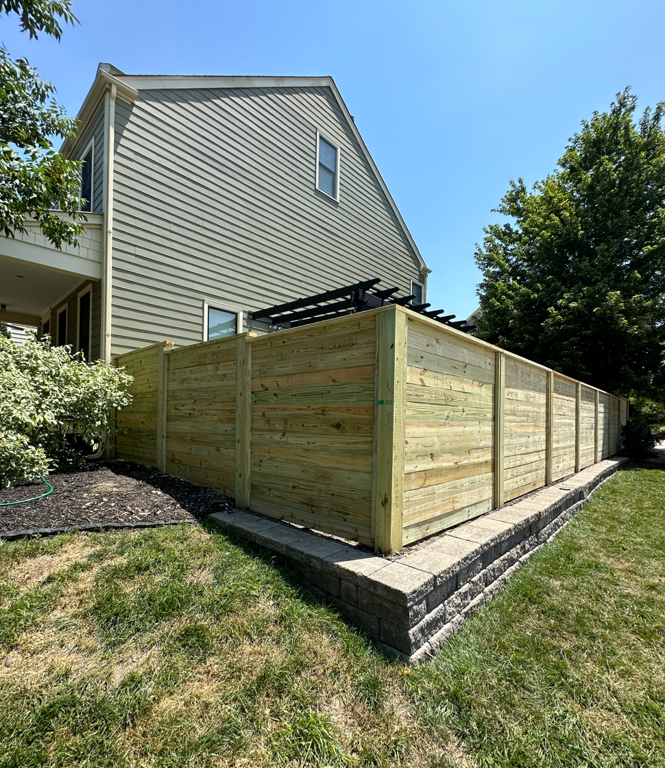 Modern wood fencing around a residential backyard patio.