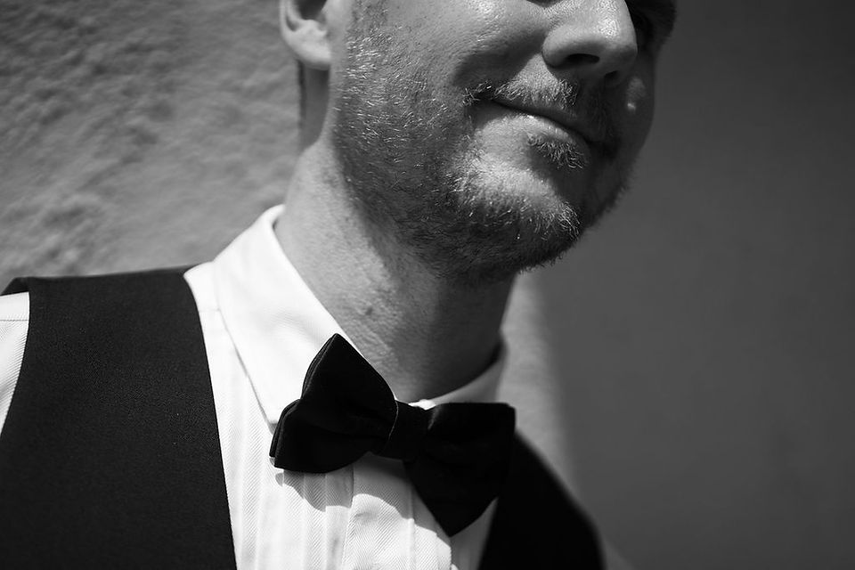 black and white close up of groom's bow tie and his smile at San Juan Mariott Resort