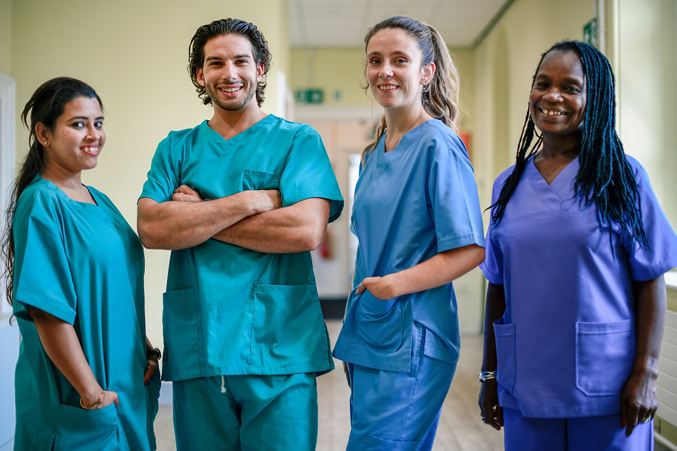 four nurses standing together in a hospital hallway, smiling at the camera