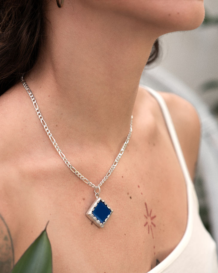 Woman wearing square blue pendant necklace