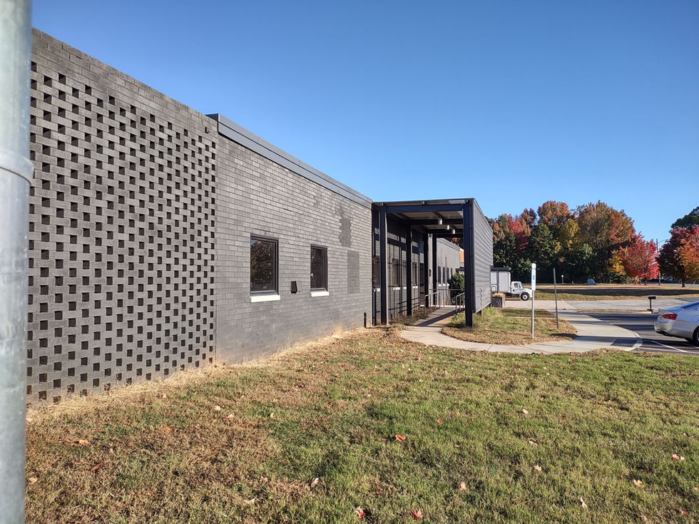 Perforated concrete block wall and modern gray brick facade at Hovis Road industrial redevelopment in Charlotte, NC, showcasing the updated exterior design with clean architectural lines and integrated windows by design by Kristina Held off Held Architecture.