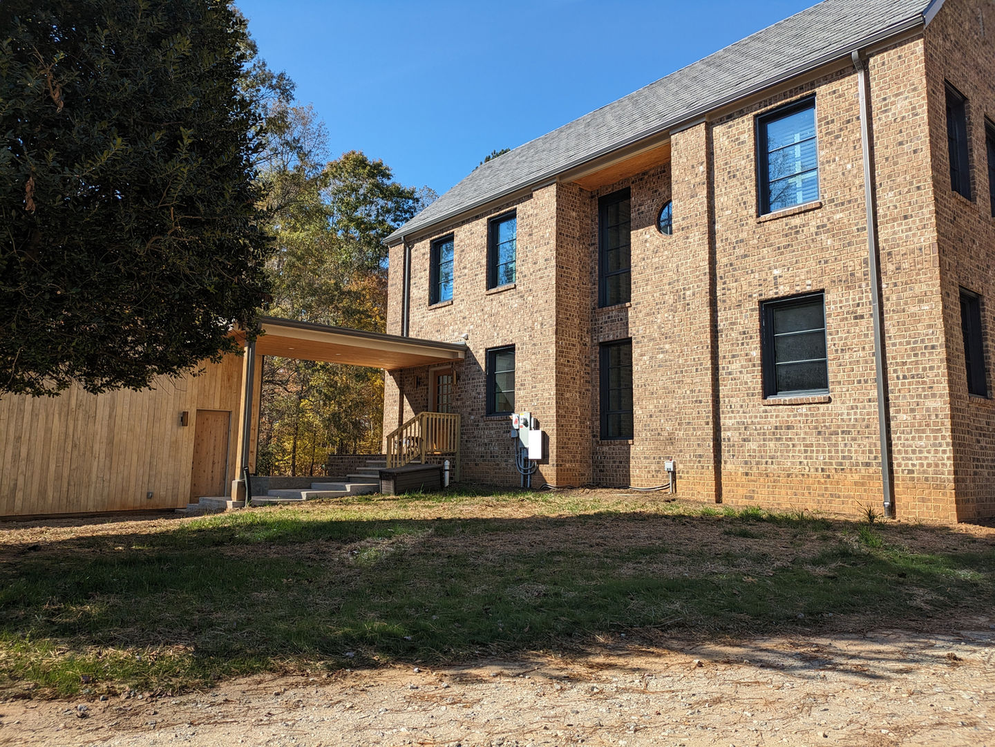 Covered connection between the wood-sided detached garage and the brick Victorian-inspired passive house designed by Held Architecture in Davidson, North Carolina. Seamless integration of modern and traditional materials.