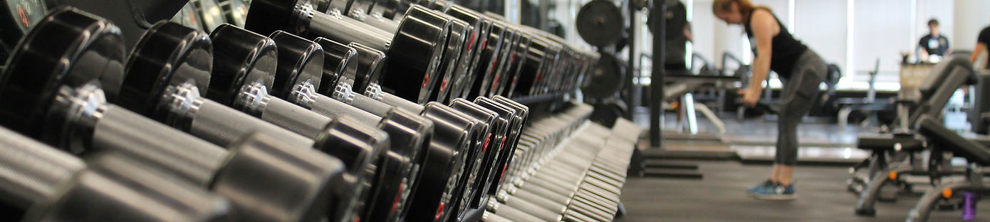 woman standing surrounded by exercise eq